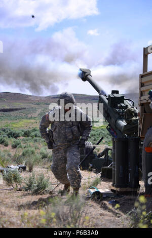An Oregon Army National Guard Soldier with Charlie Battery, 2nd Battalion, 218th Field Artillery Regiment, 41st Infantry Brigade Combat Team, takes cover after firing a familiarization round on the M777A Howitzer, May 23, during annual training at the Yakima Training Center near Yakima, Washington. This was the first time the battalion fired their newly acquired weapon system, part of the larger transformation of the 41st Infantry Brigade Combat Team. (Photo by Capt. Leslie M. Reed, 41st Infantry Brigade Combat Team Public Affairs) Stock Photo