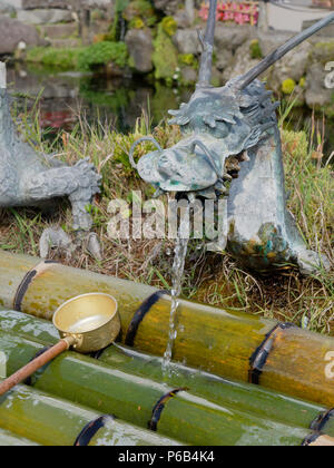 YAMANASHI, JAPAN - SEPTEMBER 26, 2017 : Spring water from dragon ornament tap of Waku pond is one of the main tourist attraction in Oshino Hakkai or springs of Mount Fuji, Oshino village Stock Photo