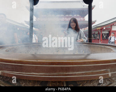 TOKYO, JAPAN - SEPTEMBER 28, 2017 : Gigantic bronze incense burner in front of Main Hall of Sensoji temple, Asakusa, where tourists bathing their hands and faces with incense smoke Stock Photo