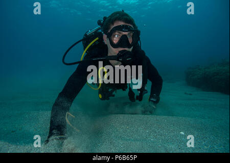 170212-N-WB378-0065 GUANTANAMO BAY, Cuba (Feb. 11, 2017) Construction Electrician 2nd Class Ben Coulson, assigned to Underwater Construction Team (UCT) 1, searches the ocean floor during diver qualification training onboard Naval Station Guantanamo Bay. UCT-1 provides a capability for construction, inspection, repair, and maintenance of ocean facilities in support of Naval and Marine Corps operations. (U.S. Navy photo by Mass Communication Specialist 1st Class Blake Midnight/Released) Stock Photo