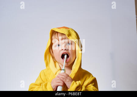 baby brushing her teeth with an electric brush Stock Photo