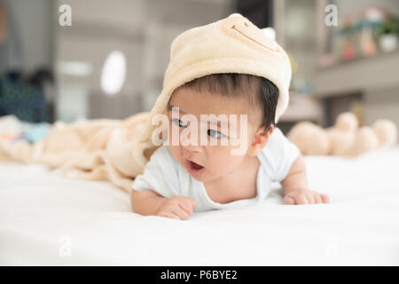 Portrait of a crawling baby on the bed in her room, Adorable baby boy in white sunny bedroom, Newborn child relaxing in bed, Nursery for young childre Stock Photo