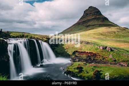 sun covered kirkjufellsfoss waterfall with kirkjufell mountain in iceland. picturesque long exposure of famous iceland Stock Photo