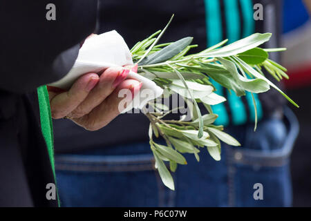 The first anniversary of the 24-storey Grenfell Tower block of public housing flats fire which claimed 72 lives. Woman holding olive branch during the memorial service in front of the tower block.  South Kensington, London, UK, 14th June 2018. Stock Photo