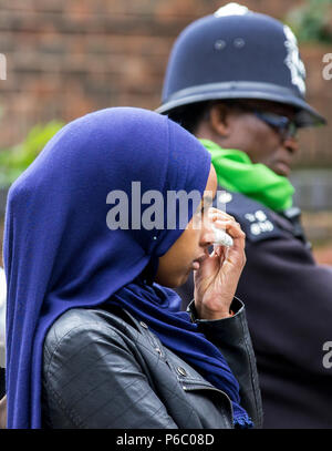 The first anniversary of the 24-storey Grenfell Tower block of public housing flats fire which claimed 72 lives. Young female wipes tears away during the public memorial service, South Kensington, London, UK, 14th June 2018. Stock Photo