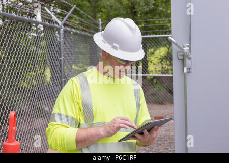 Engineer at an electric power plant checking his tablet Stock Photo