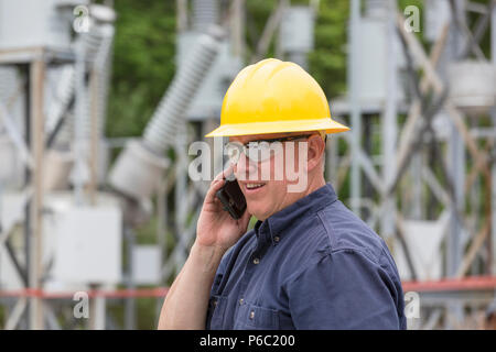 Engineer talking on cell phone at substation Stock Photo