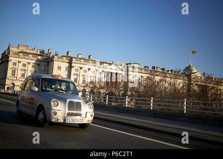 Traditional silver color London taxi driving across the bridge in the city centre of London