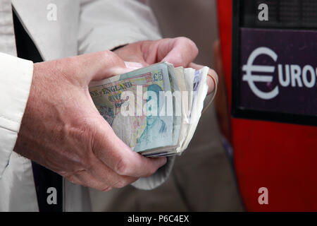 Ascot, UK, British pound notes are held in front of a euro change machine Stock Photo