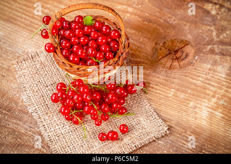 Redcurrant in basket on brown wooden table. Fresh fruits red currant on table. Stock Photo