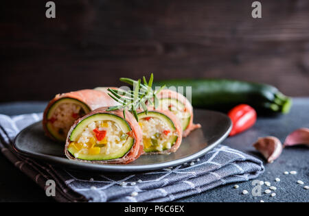 Roasted zucchini stuffed with rice, cheese, pepper and wrapped in Prosciutto slices Stock Photo