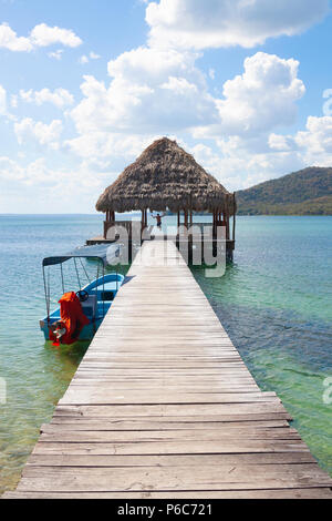 Man jumps off a wooden pier into crystal clear blue lake in Guatemala, North America Stock Photo