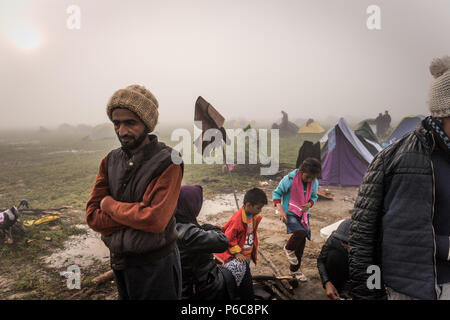 The family warm themselves and dries they wet cloths by the bonfire at the makeshift refugee camp of the Greek-Macedonian border near the Greek villag Stock Photo