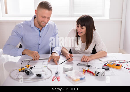 Smiling Young Male And Female Architect Working On Blueprint In Office Stock Photo