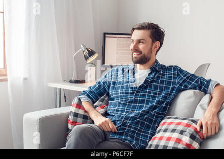 Young man leisure at home sitting looking out the window joyful Stock Photo