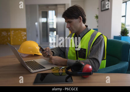 Male worker using mobile phone at desk Stock Photo