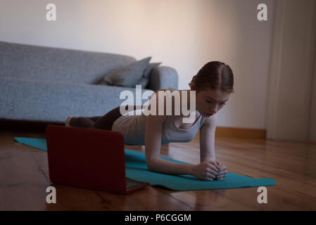 Woman practicing plank pose in living room Stock Photo