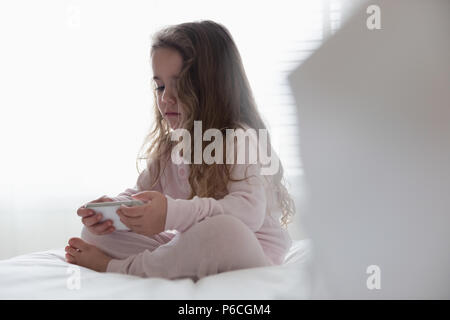 Little girl using mobile phone in bedroom Stock Photo