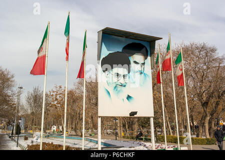 Images of Ali Khamenei, Supreme Leader of the Islamic Revolution and Ruhollah Khomeini on a billboard flanked my flag poles with the Iranian flag at t Stock Photo