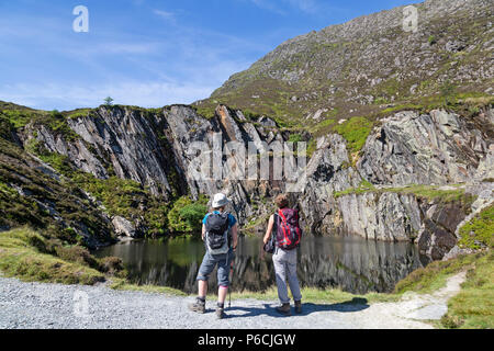 Two female hikers looking at a disused and flooded slate quarry situated on the track up to Moel Siabod, a mountain in the Snowdonia National Park. Stock Photo