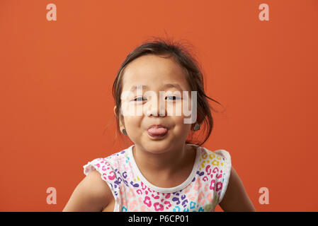 Asian girl show tongue. Funny portrait of little asian girl Stock Photo