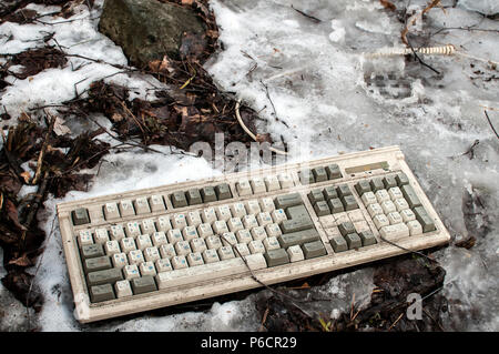 Abandoned dirty broken grunge computer keyboard on snowy frozen soil Stock Photo