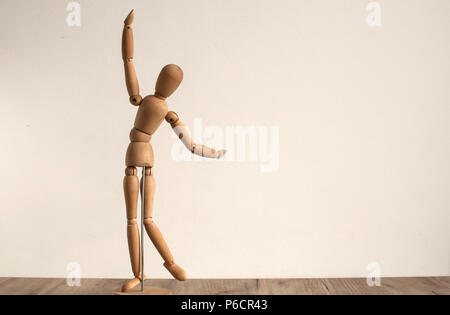 Wooden dummy toy poses on white wall background Stock Photo