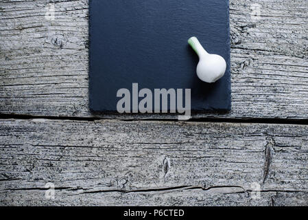 Young onion on a small blackboard on a wooden background. Stock Photo