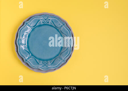 Two rustic plates on yellow background. Plates on left side of frame. Top view. Stock Photo