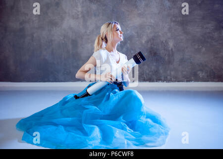 Young woman dreams of the future, concept. Girl looks up and uses a telescope. Dream and set goals, look through the telescope. Grey textured backgrou Stock Photo