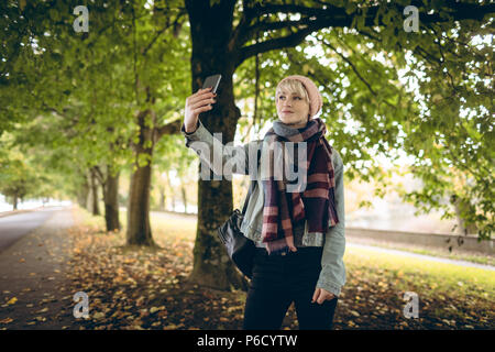 Young woman in warm clothing clicking selfie Stock Photo