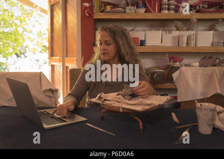 Female potter using laptop Stock Photo