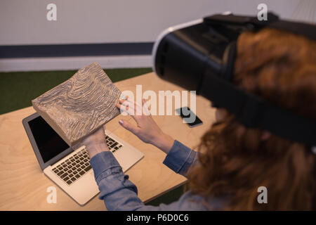 Woman touching wooden slab while using virtual reality headset Stock Photo