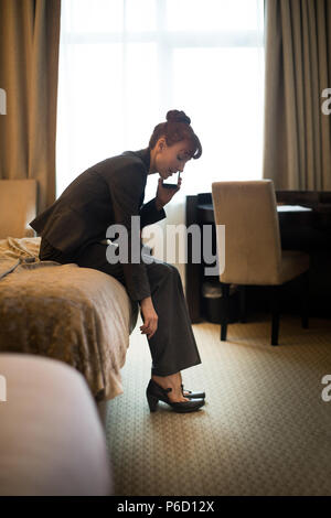 Businesswoman talking on mobile phone while wearing shoes Stock Photo