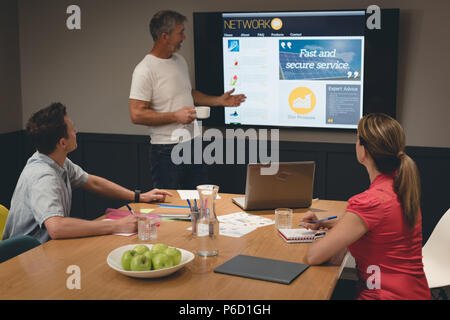 Businessman giving presentation to colleagues in meeting room Stock Photo