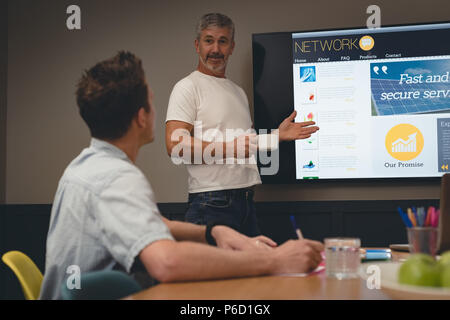 Businessman giving presentation to colleagues in meeting room Stock Photo