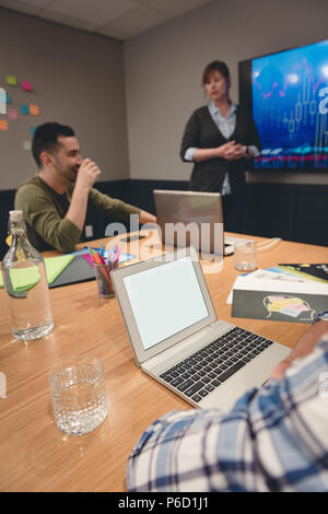 Businesswoman giving presentation to colleagues in meeting room Stock Photo
