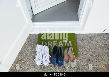 Various shoes kept on a door mat Stock Photo