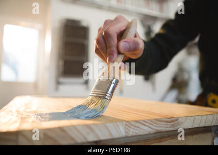 Male carpenter painting a table
