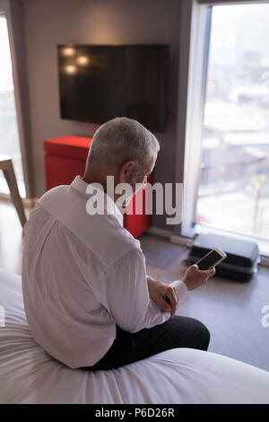 Businessman using a smart phone on bed Stock Photo