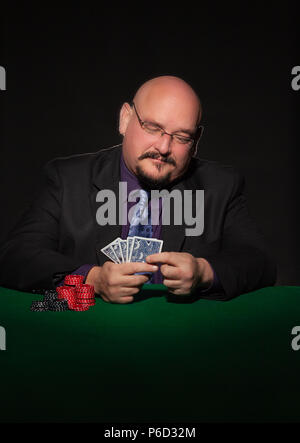 card player in business suit.  Glasses and necktie with gaming chips against black background. Stock Photo