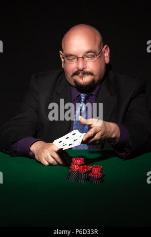 card player in business suit.  Glasses and necktie with gaming chips against black background. Stock Photo