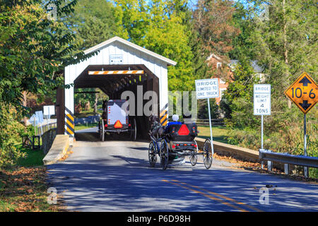 Strasburg, PA, USA - October 1, 2017: Amish buggies enter the Strasburg Covered Bridge on sunny Autumn day in Lancaster County. Stock Photo