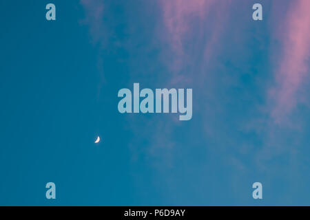 Half moon. Growing yellow crescent at blue turquoise sky with fairy pink long clouds. Copyspace Stock Photo