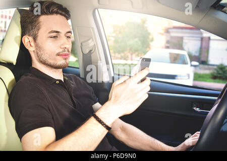 Photo of a handsome man using mobile phone while driving. Stock Photo
