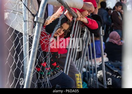 Children behind railings close to the gate as they wait to cross the border at the makeshift refugee camp of the Greek-Macedonian border near the Gree Stock Photo