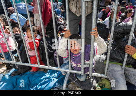 Children behind railings close to the gate as they wait to cross the border at the makeshift refugee camp of the Greek-Macedonian border near the Gree Stock Photo