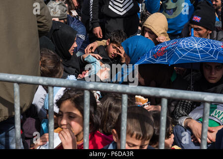 Refugee gather behind railings close to the gate as they wait to cross the border at the makeshift refugee camp of the Greek-Macedonian border near th Stock Photo