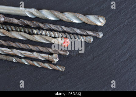 Various old masonry drill bits on slate Stock Photo