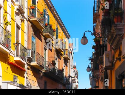 Italian narrow street with colorful houses, street light and blue sky between on sunny summer day. Vietri sul Mare, South of Italy